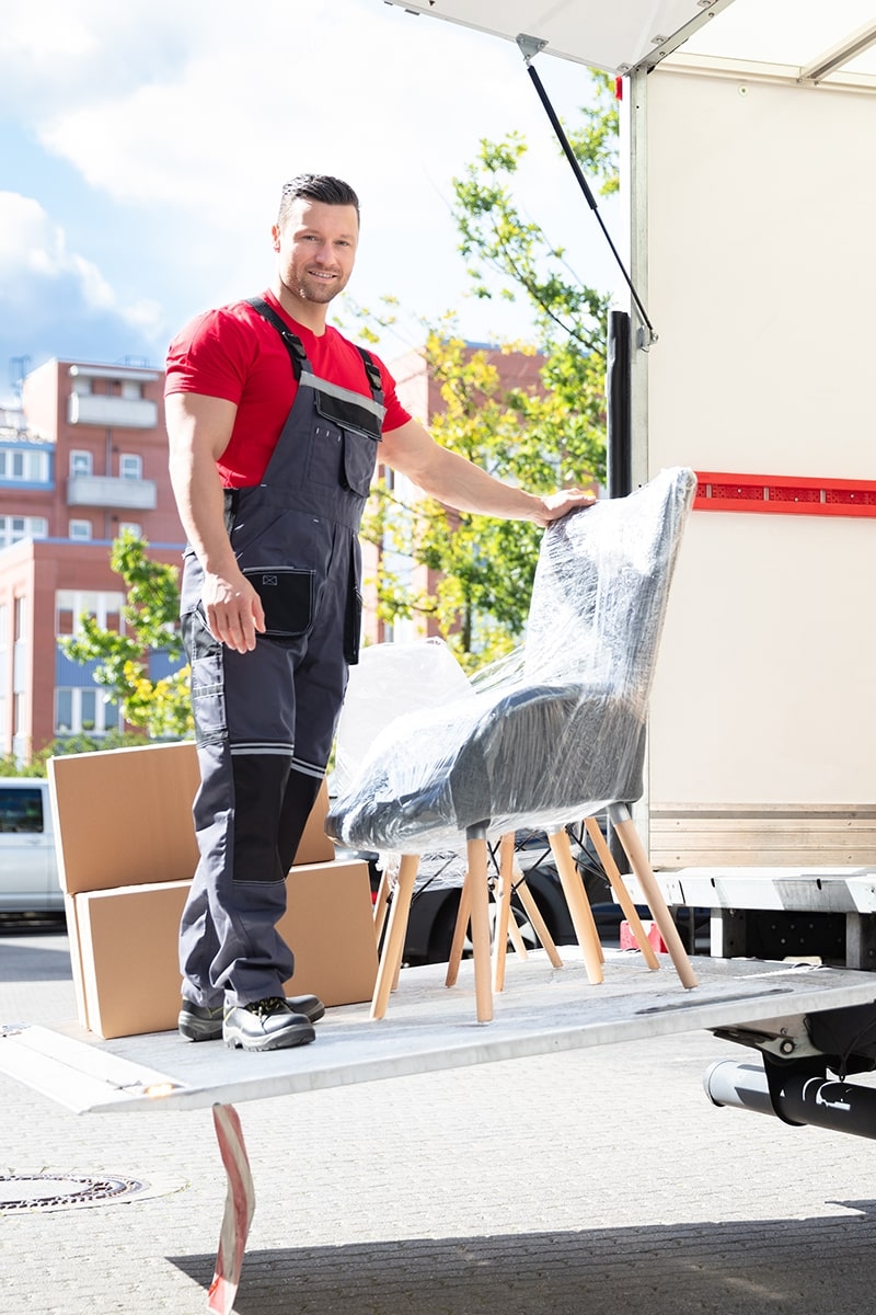 Umzughelfer lädt Möbel und Kartons aus einem LKW aus