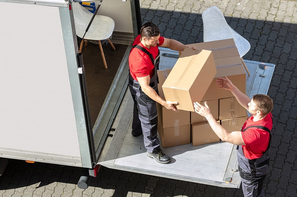 Zwei Umzugshelfer laden Kartons aus einem LKW